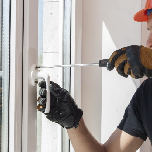 master with a screwdriver sets fittings on the window